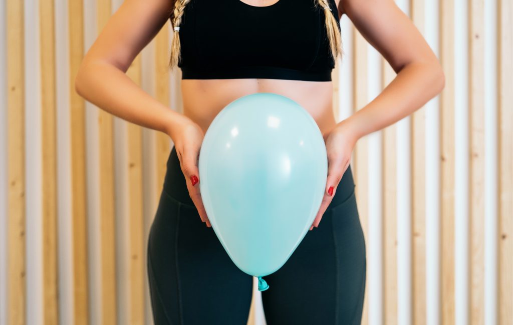A woman holding a balloon in front of her pelvic area