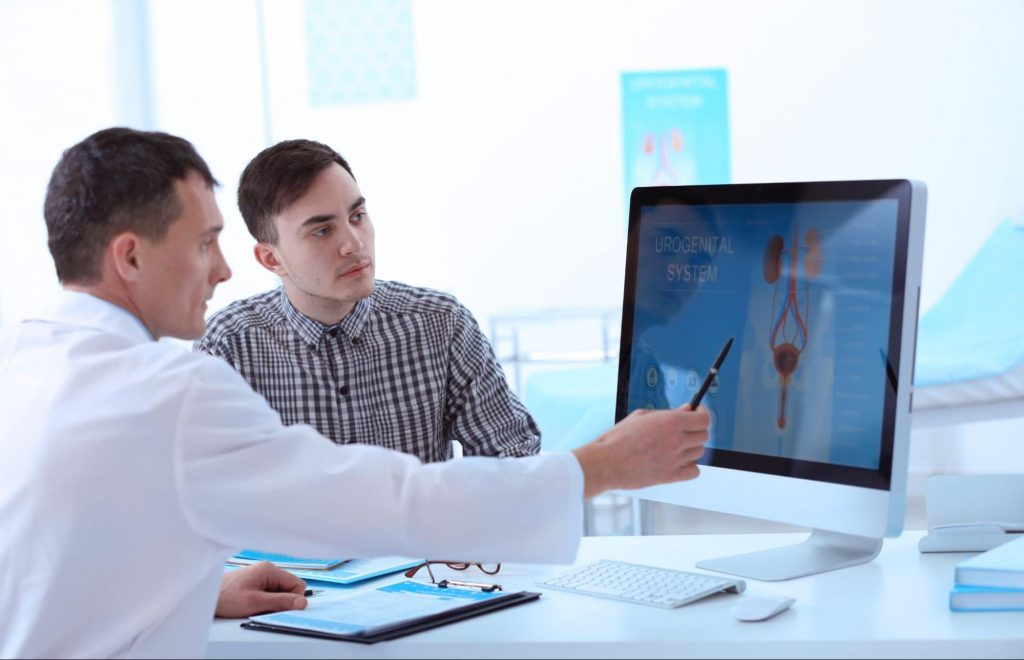 A urologist explaining a diagram on a computer screen to his patient to represent clearing up myths about urology