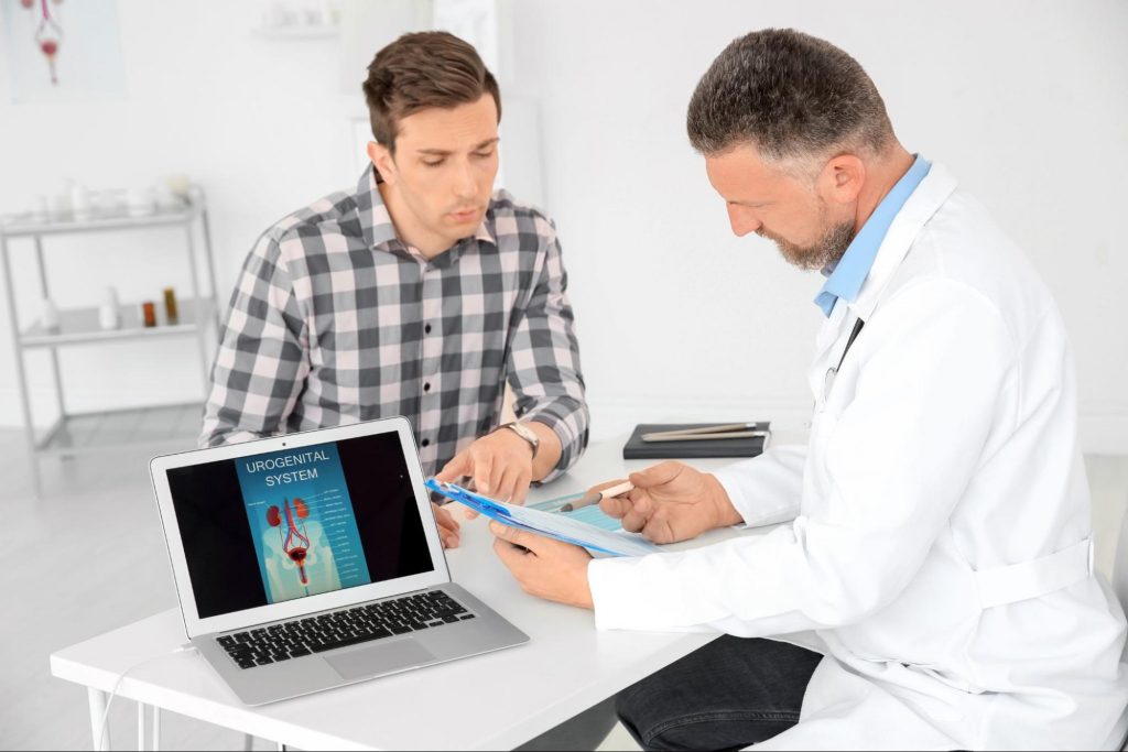 A doctor sitting with a patient at a desk to explain What You Need to Know About Vasectomy Reversals